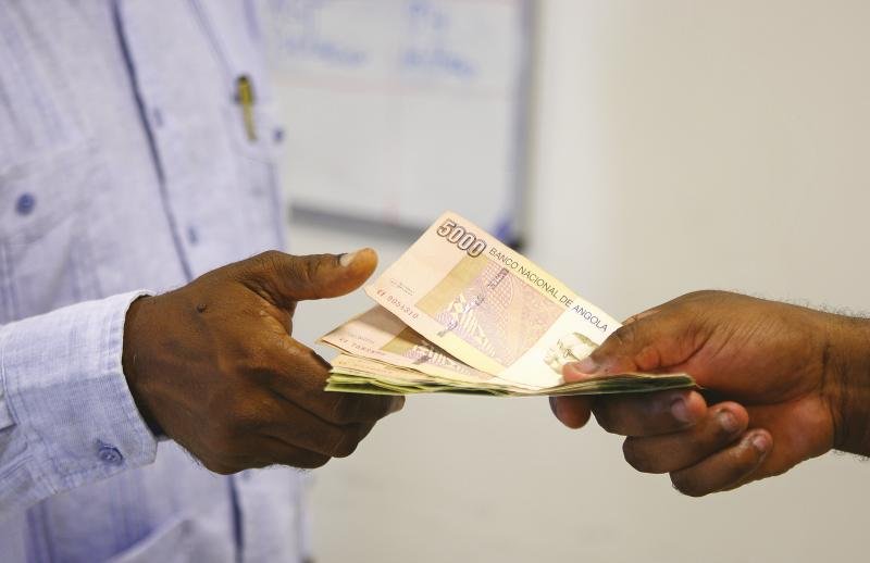 Grupo de vendedores angolanos do mercado do Prenda realizando encontro de kixikila, sistema tradicional de poupança rotativa que sustenta pequenos empreendedores em Angola