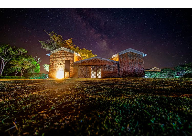 Vista exterior do Mumba Lodge na Fazenda Mumba, mostrando as suites exclusivas integradas na paisagem natural entre as províncias da Huíla e Cuando
