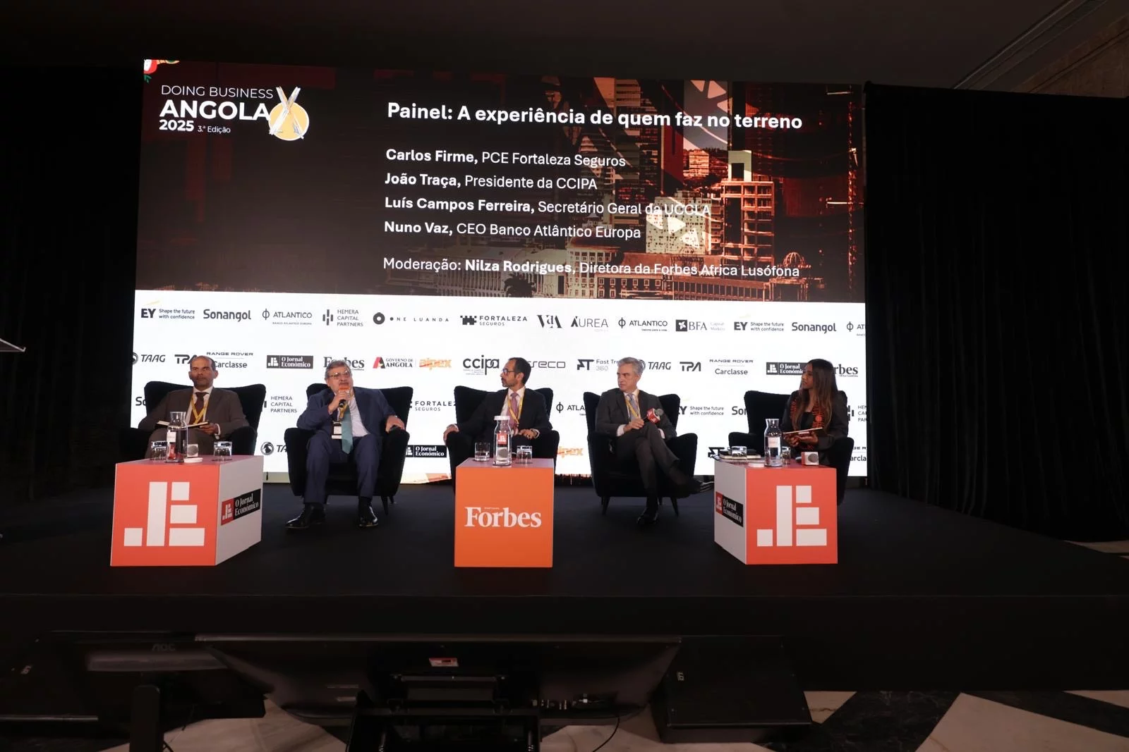 Painel de discussão do evento Doing Business Angola 2025 em Lisboa com executivos portugueses e angolanos debatendo oportunidades de negócio bilateral"